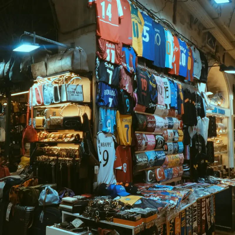 Football jerseys and bags displayed in a market stall