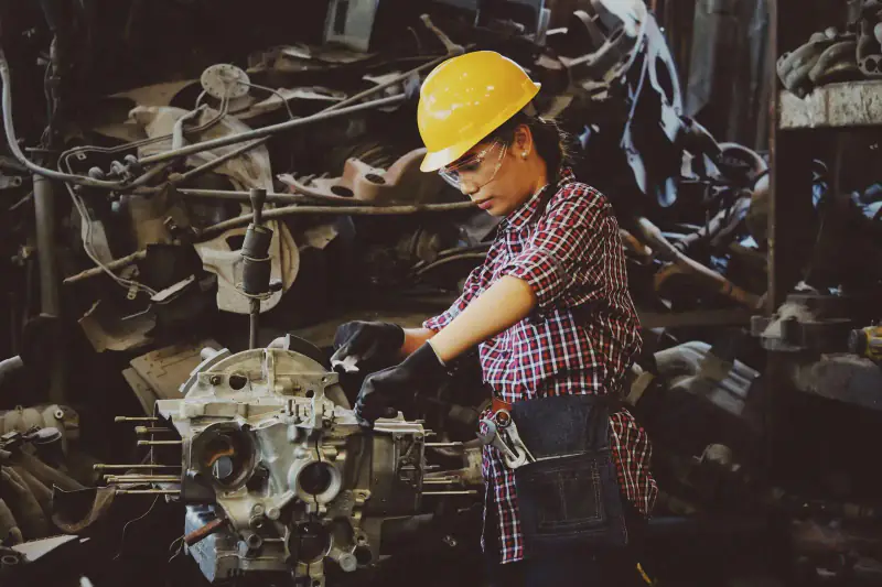 Woman in a hard hat working on an engine