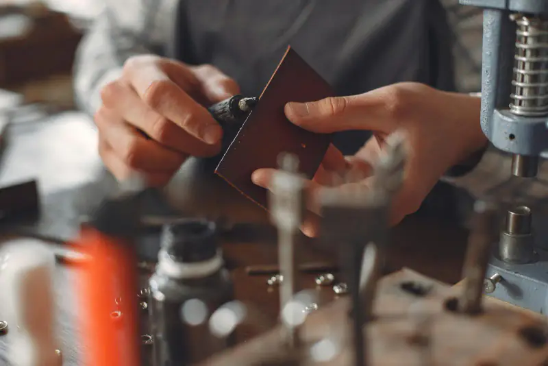 Hands marking leather at a workbench