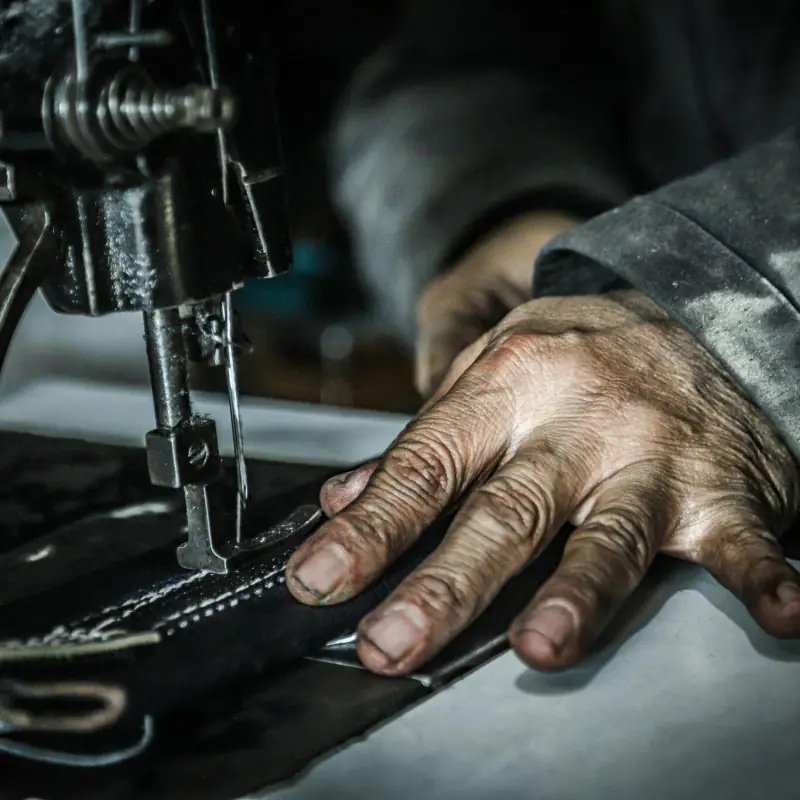 Weathered hand guiding fabric at a sewing machine